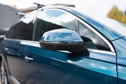 Close up view of mirror on outside of car passenger door on high-trim vehicle. Image formed in reflecting surface giving wide field of traffic view