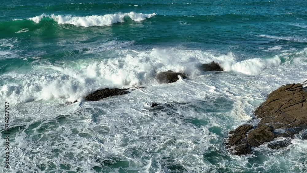 Slow Motion of Bubbling Blue Ocean Water breaking rocks with White Foam on a sunny day Slow Motion of Bubbling Blue Ocean Water breaking rocks with White Foam on a sunny day