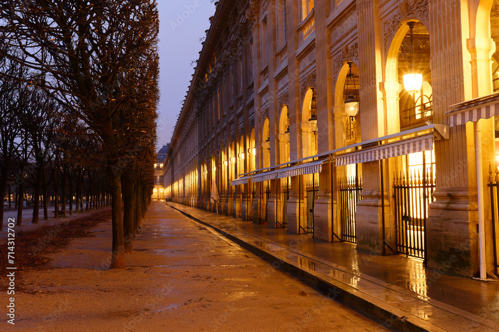 The wall of arches, columns and arcades bordering the Royal Palace Garden at rainy night. Paris. France.