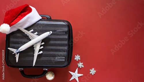 pack your dreams for new year top view image of a suitcase miniature airplane model and santa s hat on a vibrant red backdrop offering space for your new year aspirations photo