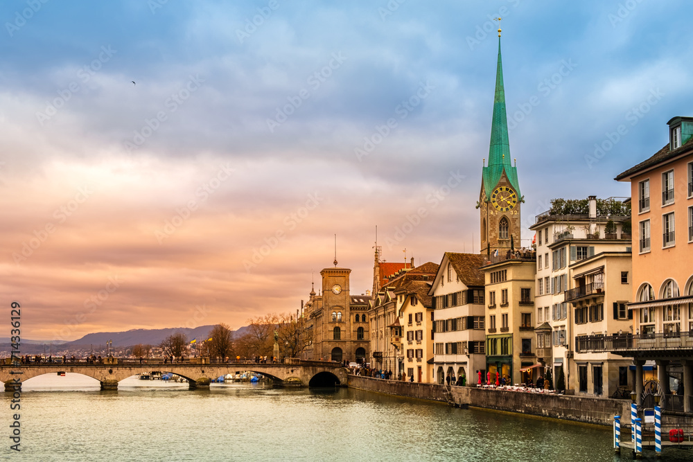Zurich city center, Switzerland. Zuerich old town with famous Fraumunster and Munsterbrucke bridge on bank of river Limmat at sunset with dramatic sky in winter