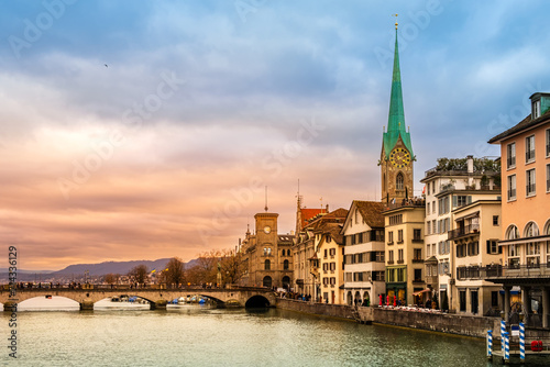 Zurich city center, Switzerland. Zuerich old town with famous Fraumunster and Munsterbrucke bridge on bank of river Limmat at sunset with dramatic sky in winter photo