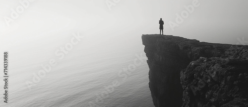 dramatic black and white image of a lone figure standing on a cliff overlooking the sea, reciting poetry to the vast ocean, symbolizing freedom and the power of words photo
