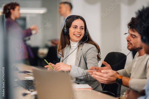 Фотография A telemarketer is sitting at call center and having a phone call.