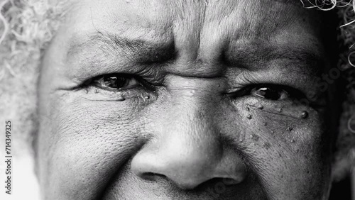 One serious senior black woman staring at camera with solemn expression in monochromatic, black and white. Macro closeup of African American person eyes and face photo