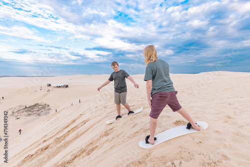 KIds sand boarding on the sand dunes at Birubi Beach in Port Stephens, NSW Australia photo