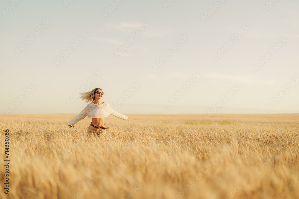 A woman exudes happiness as she spreads her arms wide, enjoying the freedom of the vast, golden wheat field under the open sky A woman exudes happiness as she spreads her arms wide, enjoying the freedom of the vast, golden wheat field under the open sky