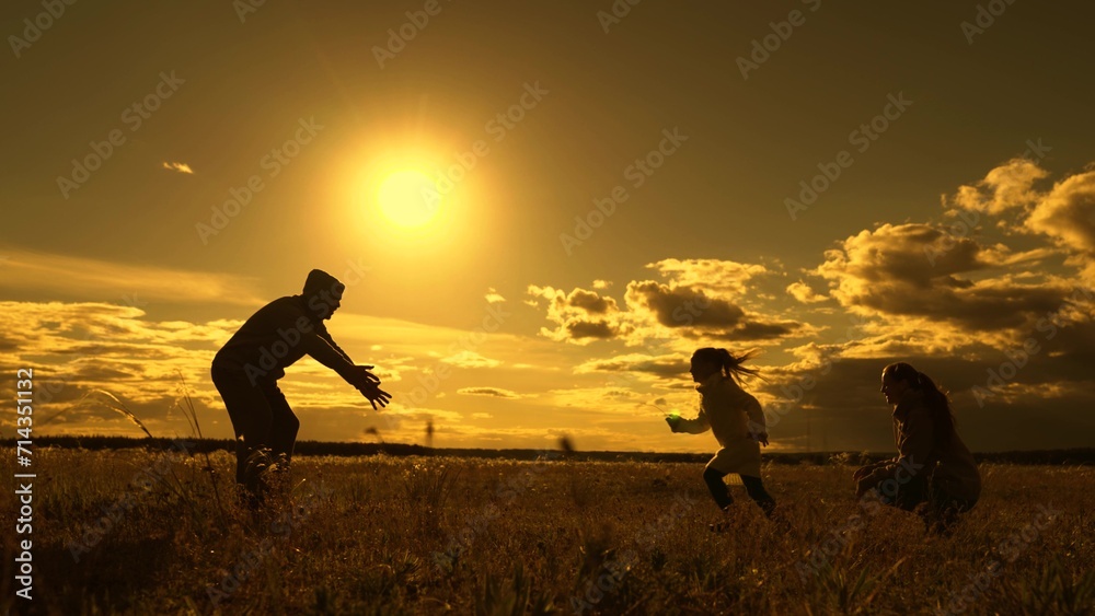 Child runs from mother to father, hugs parents, family game. Happy family, dad spins his daughter in his arms in park under sun. Family walks in park in autumn. Parents, kid in nature. People outdoors