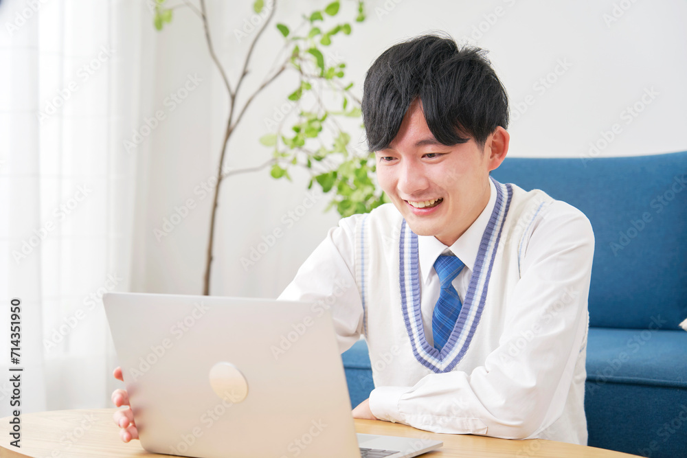 リビングでノートパソコンで動画を見る男子高校生