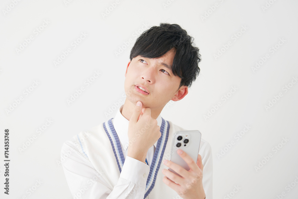 スマートフォンを持って考える男子高校生 白背景 スマートフォンを持って考える男子高校生 白背景