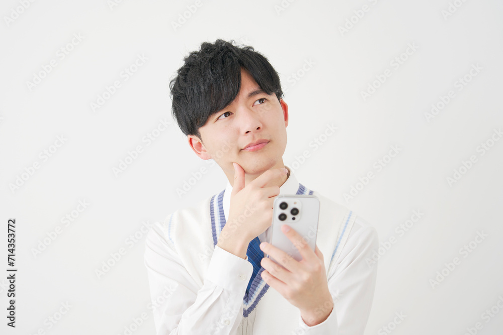 スマートフォンを持って考える男子高校生　白背景