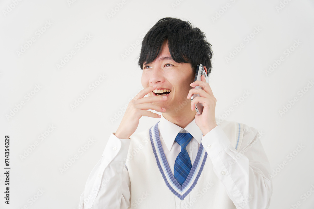 スマートフォンで電話しながら笑顔で驚く男子高校生　白背景
