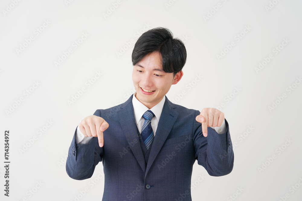 下を指差す若いビジネスマン　白背景