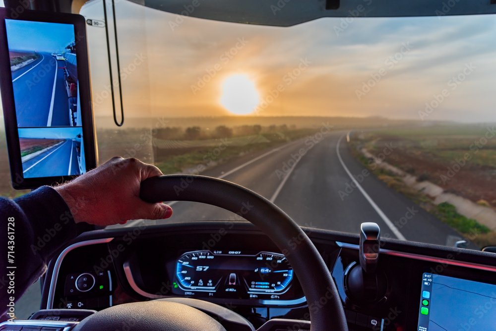 View from the driver's seat of a truck with camera rearview mirrors of a conventional road at dawn, interior of the vehicle.