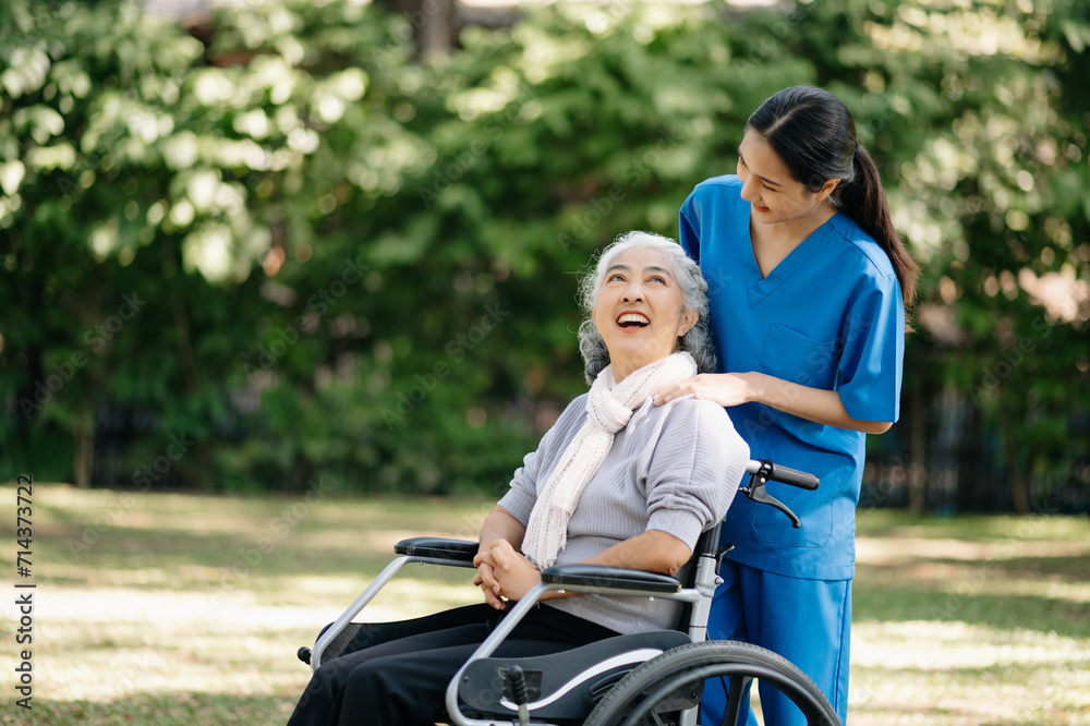 Elderly asian senior woman on wheelchair with Asian careful caregiver and encourage patient, walking in garden. with care from a caregiver and senior health insurance... Elderly asian senior woman on wheelchair with Asian careful caregiver and encourage patient, walking in garden. with care from a caregiver and senior health insurance...
