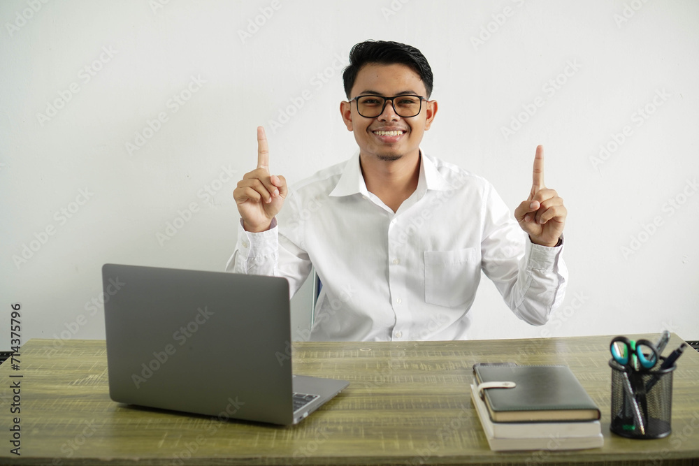 young asian businessman in a workplace pointing up a great idea, wearing white shirt with glasses isolated young asian businessman in a workplace pointing up a great idea, wearing white shirt with glasses isolated
