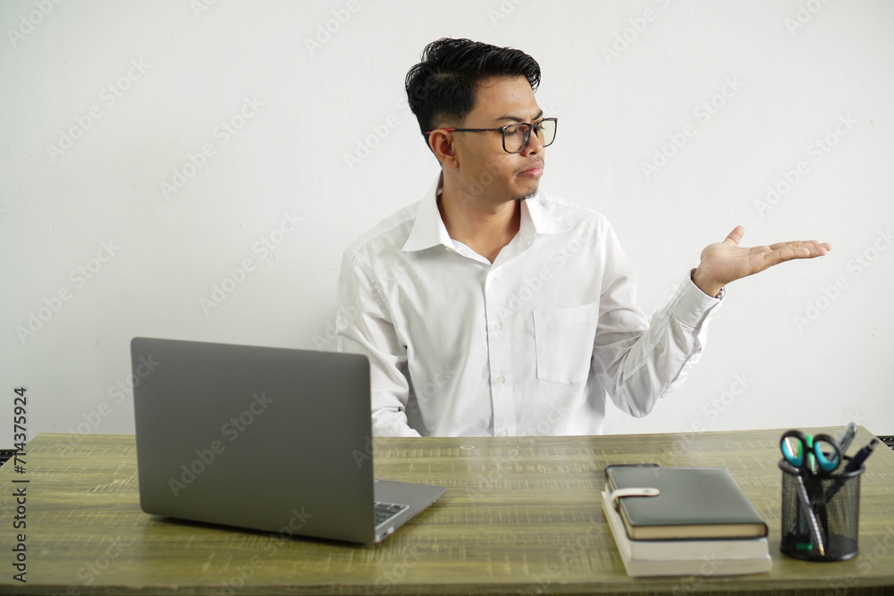 young asian businessman in a workplace holding copy space with doubts, wear white shirt with glasses isolated young asian businessman in a workplace holding copy space with doubts, wear white shirt with glasses isolated