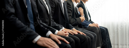 Group of interviewee candidate in formal suit line up for interview sitting on the chair. Job opportunity recruitment for HR agency and vacancy concept. Shrewd photo