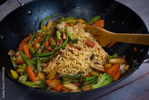 Vegan mixed vegetables stir fry in wok along with ramen noodles