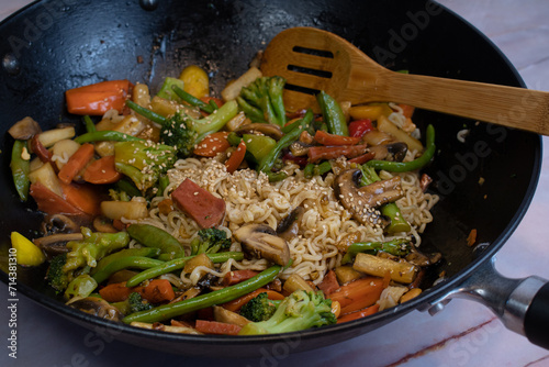 Vegan mixed vegetables stir fry in wok along with ramen noodles