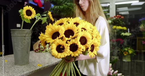 A florist at a flower store assembles a bouquet of sunflowers