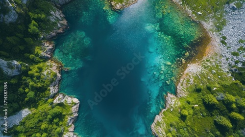 an aerial view of a body of water surrounded by lush green trees and a rocky cliff on the other side of the water is a deep blue body of water.