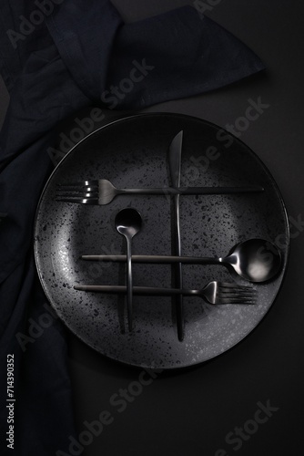 Stylish table setting. Plate  napkin and cutlery on black background  top view