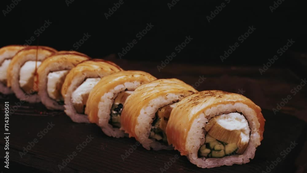 Chef cooking making sushi, pouring sauce sprinkles with sesame seeds. 4k footage Fresh Sushi Falling Soy Sauce. Japanese sushi roll on black wooden background. Asian Food, Sushi Restaurant close up Chef cooking making sushi, pouring sauce sprinkles with sesame seeds. 4k footage Fresh Sushi Falling Soy Sauce. Japanese sushi roll on black wooden background. Asian Food, Sushi Restaurant close up