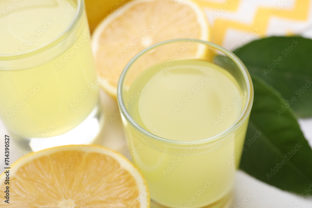 Tasty limoncello liqueur and lemons on table, closeup Tasty limoncello liqueur and lemons on table, closeup