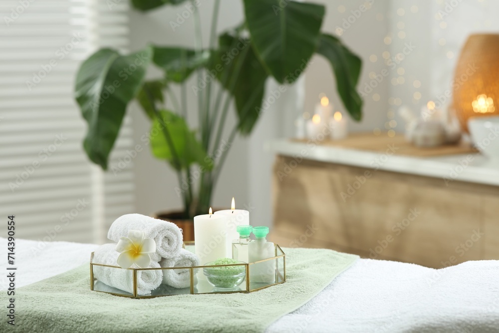 Composition with different spa products and burning candles on table indoors. Space for text
