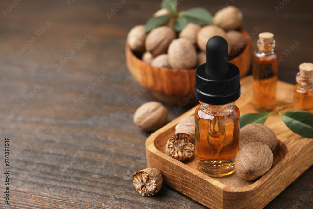 Nutmeg essential oil and nuts on wooden table, closeup. Space for text Nutmeg essential oil and nuts on wooden table, closeup. Space for text