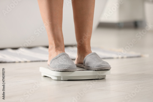 Menopause, weight gain. Woman standing on floor scales indoors, closeup