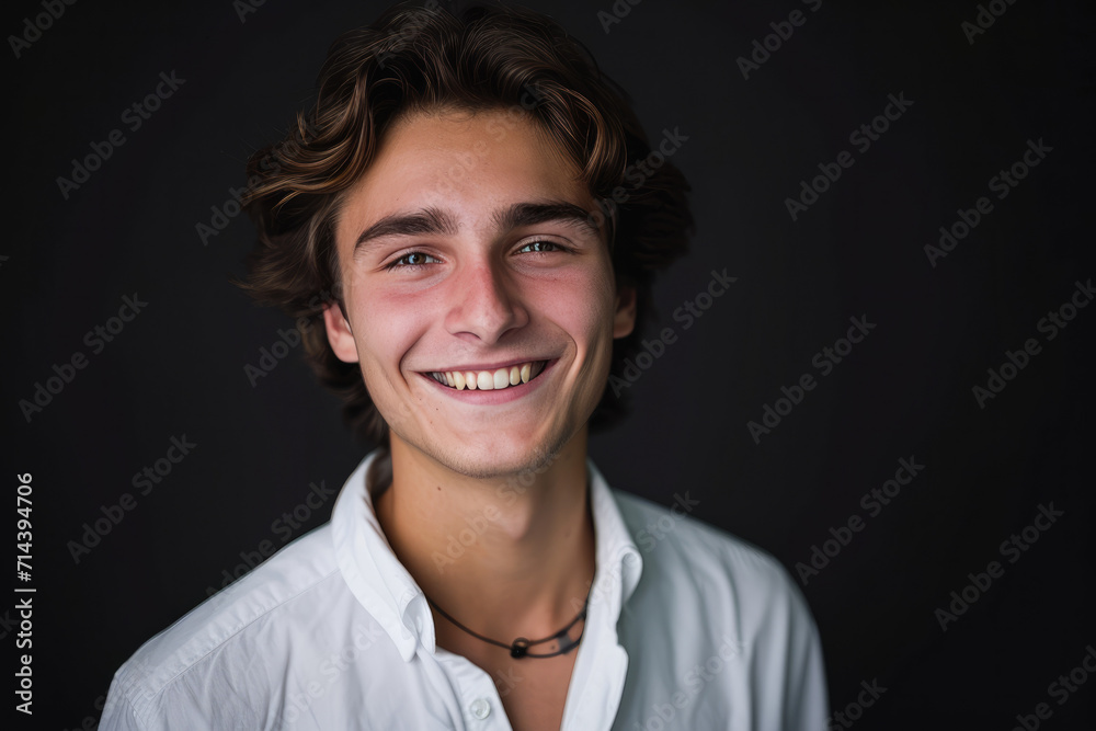 A young man in a white shirt smiles for the camera A young man in a white shirt smiles for the camera
