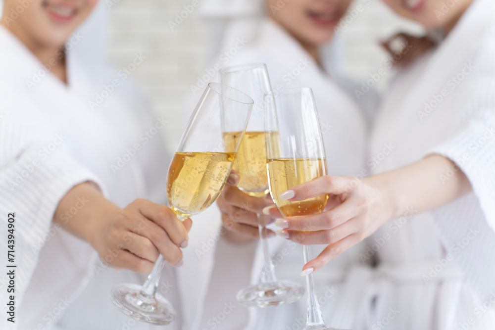 close-up of three young women wearing white bathrobes and wet hair wrapped in fluffy white towels hold wine glasses outstretched close-up of three young women wearing white bathrobes and wet hair wrapped in fluffy white towels hold wine glasses outstretched