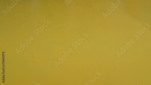 painting a yellow wall with a roller.