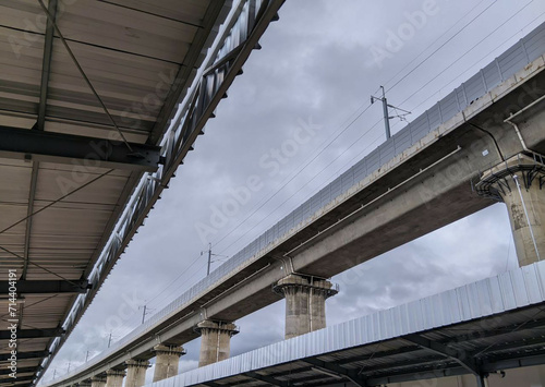 A photograph capturing the cloudy sky above a train station and its railway tracks.