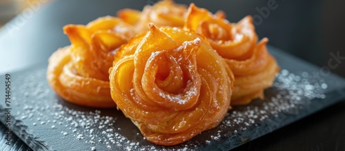 Moroccan pastries resembling a rose, fried to golden perfection, topped with homemade syrup on a slate plate with a handmade tablecloth. photo