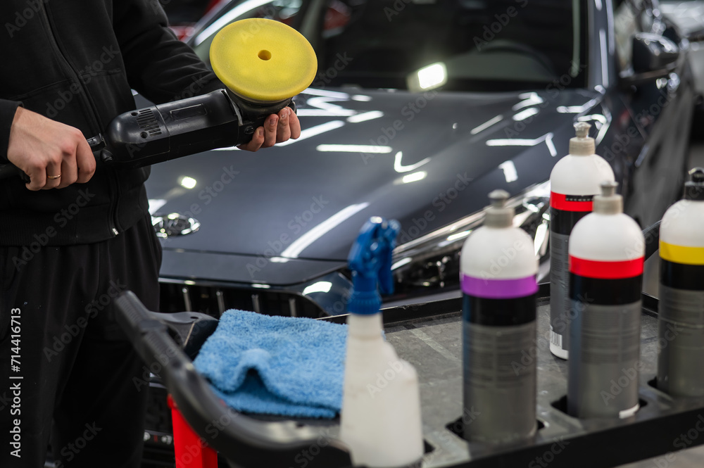 The master applies a special composition to the device for polishing the surface of the car body. 