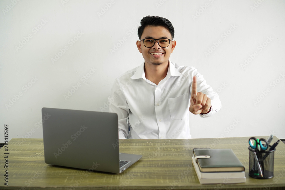 young asian businessman in a workplace showing and lifting a finger, wear white shirt with glasses isolated young asian businessman in a workplace showing and lifting a finger, wear white shirt with glasses isolated