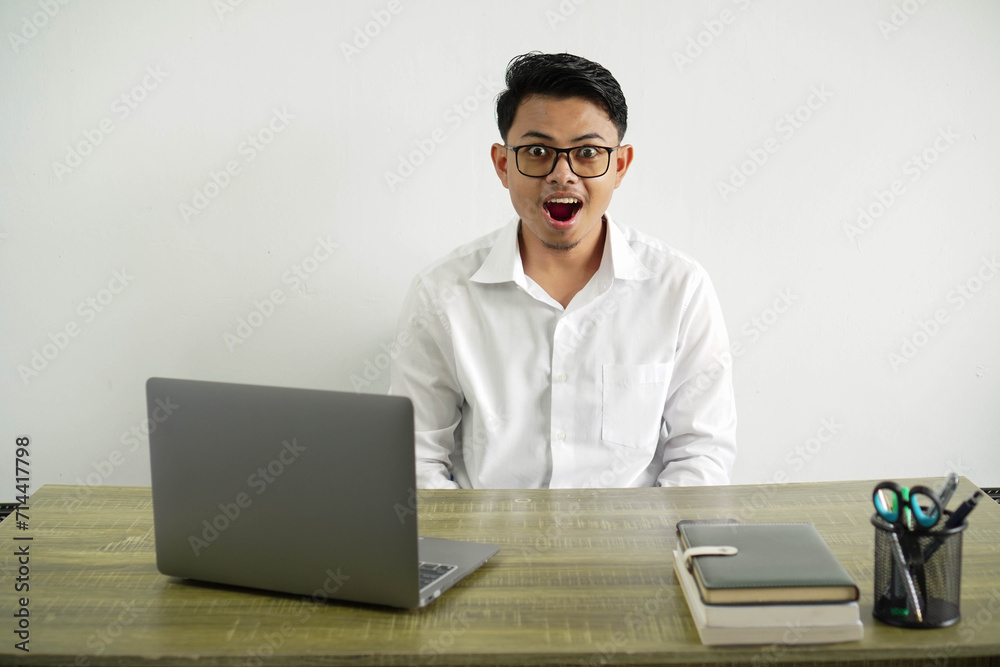 young asian businessman in a workplace with surprise facial expression, wearing white shirt with glasses isolated young asian businessman in a workplace with surprise facial expression, wearing white shirt with glasses isolated