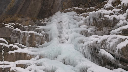 Freezing waterfall in snowy mountains. Crystal clear icicles frozen at snowy waterfall. Aelggialp, canton Obwalden, Switzerland. photo