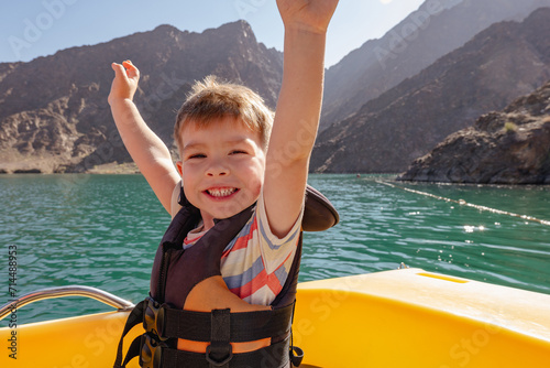 happy smiling little boy enjoying sailing on a mountain lake on a catamaran. Summer travel and holidays with children photo
