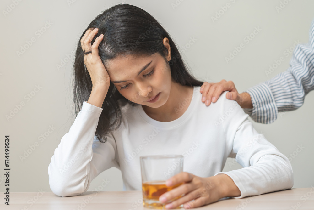Alcoholism drunk asian young woman hand holding glass of alcohol or whiskey, female sitting alone, drinking on table at home, at night. Treatment of alcohol addiction, suffer abuse problem alcoholism Alcoholism drunk asian young woman hand holding glass of alcohol or whiskey, female sitting alone, drinking on table at home, at night. Treatment of alcohol addiction, suffer abuse problem alcoholism