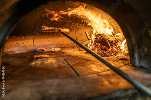Traditional oven for baking pizza with burning wood and shovel. Neapolitan pizza is finished on a shovel in a brick oven photo
