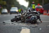 A tragic scene of a motorcycle accident with the bike lying on the road and a helmet and other personal items scattered around.