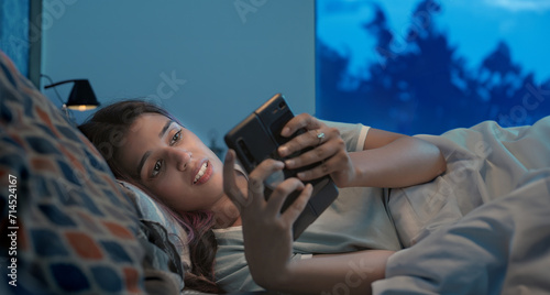 фотографія Indian Asian Hindu gen z upset sad alone young woman lady crying lying on bed use mobile check sms late night indoor home