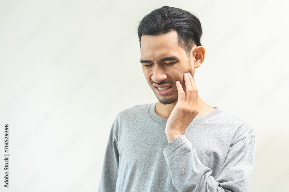 Portrait of male face suffering from sensitive teeth, tooth pain asian young man feeling hurt hand touching cheek and mouth. Health care, medicine of toothache. Dental decay problem, dentist treatment Portrait of male face suffering from sensitive teeth, tooth pain asian young man feeling hurt hand touching cheek and mouth. Health care, medicine of toothache. Dental decay problem, dentist treatment