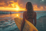 Close-up back view of a beautiful surfer woman holding a surfboard at the beach at sunset