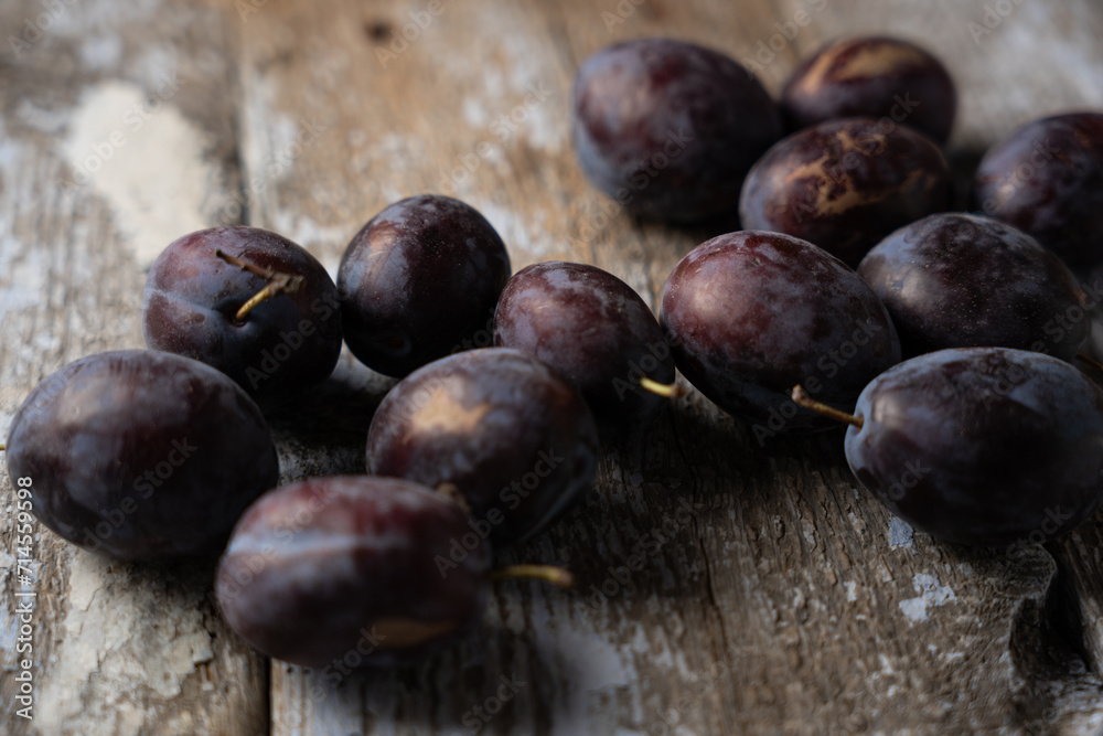 Fototapeta premium Ripe plums on a wooden old background, horizontal format, macro