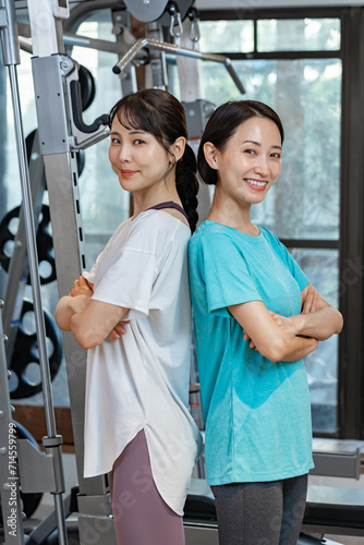 ジムで腕組をするトレーニングウェアを着た女性2人